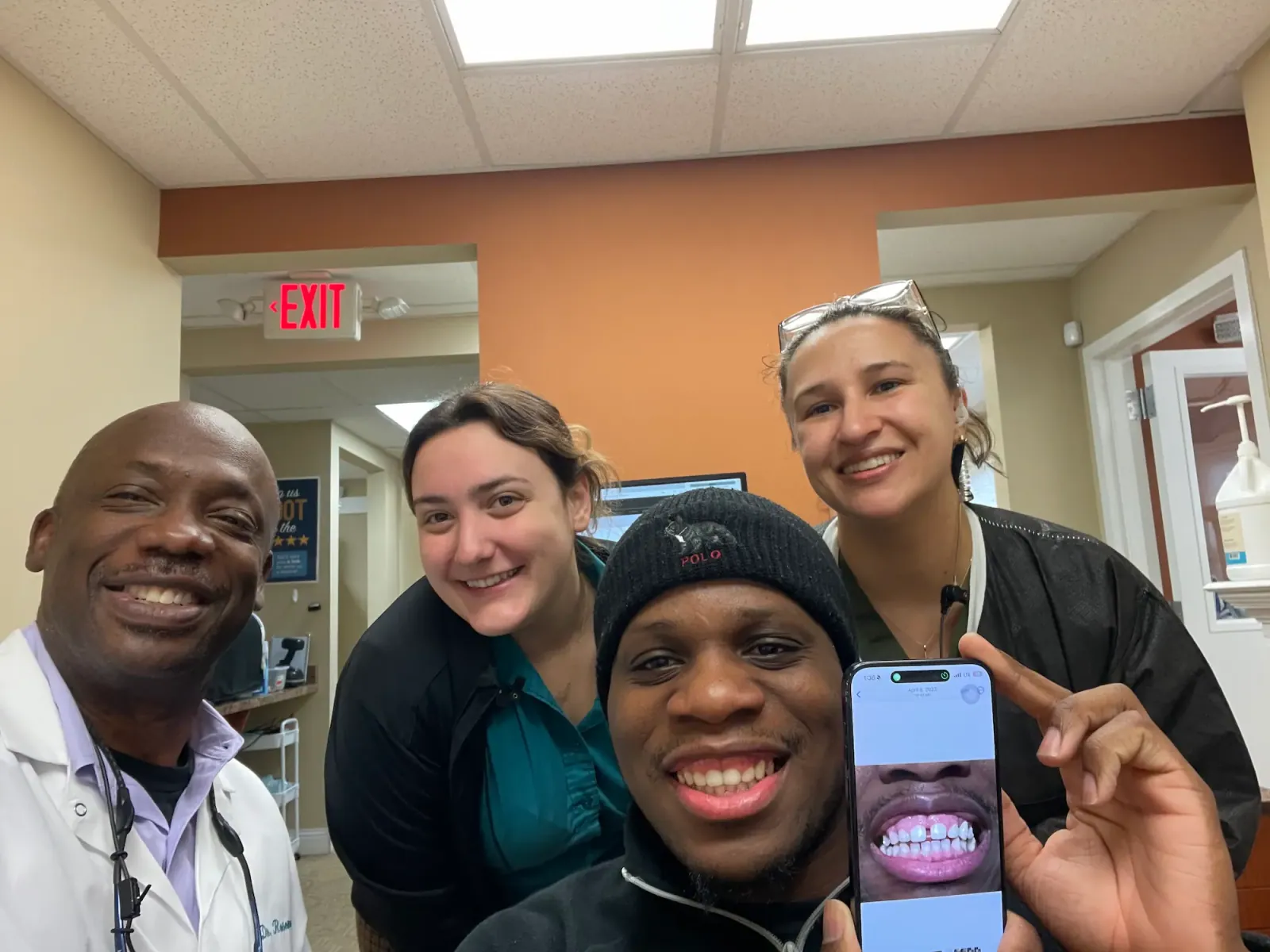 Dr. Rosemond and the team with a patient showing off his new smile on his phone